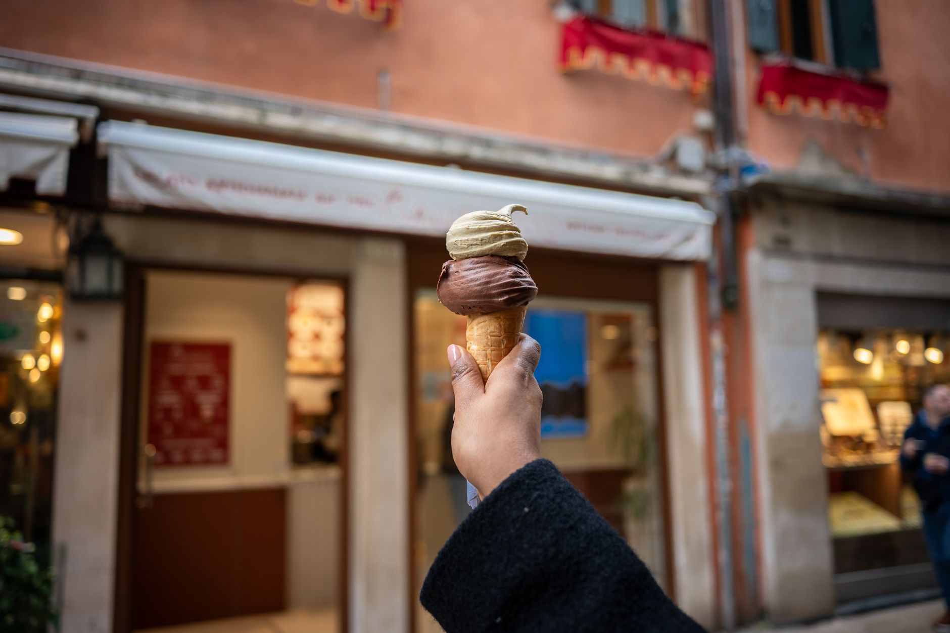 Cono con pistacchio e cioccolato tenuto in mano per strada